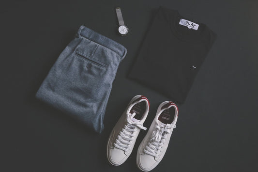 White sneakers beside pants, a shirt and a watch