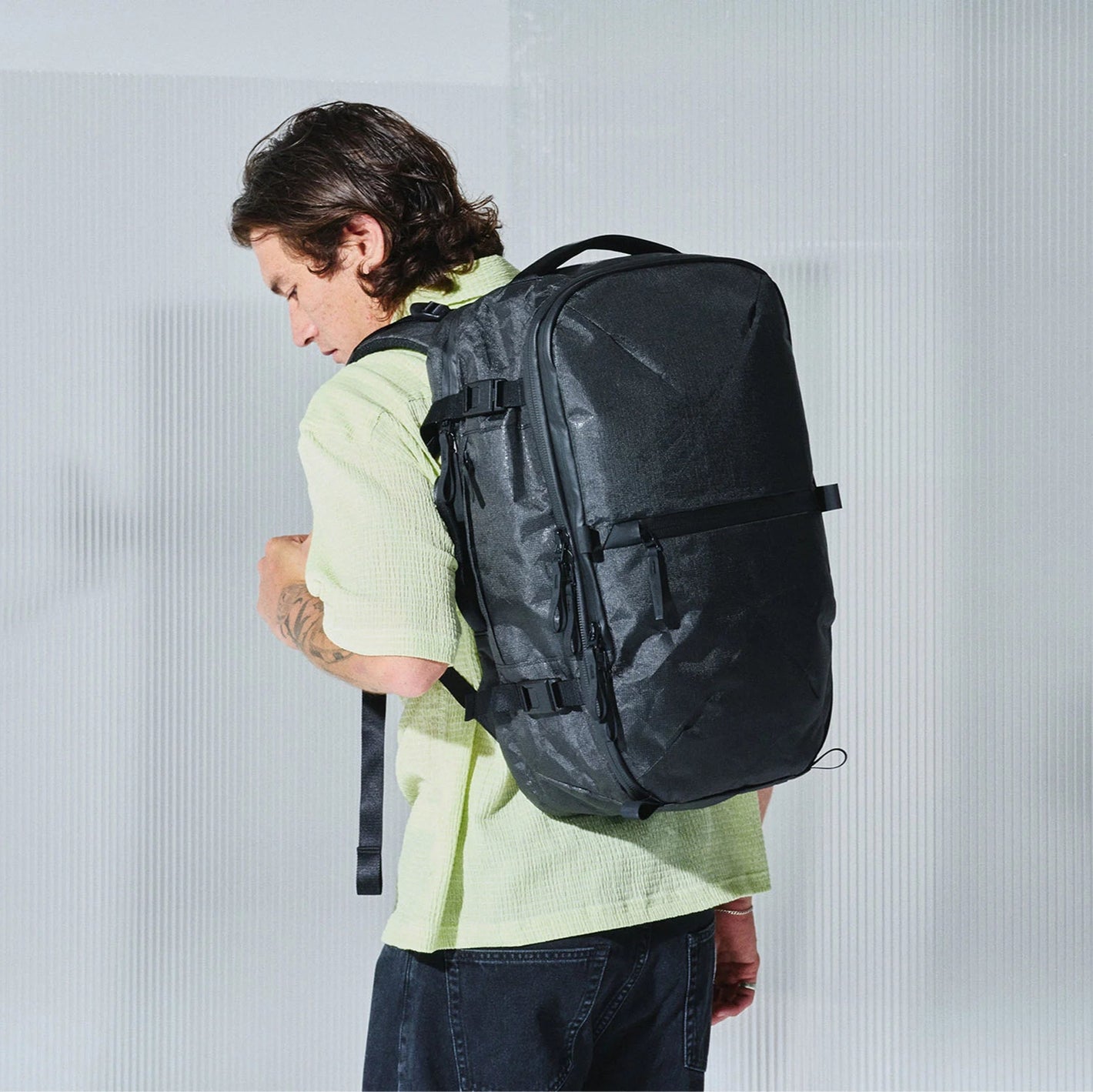 Person wearing a black backpack against a plain background