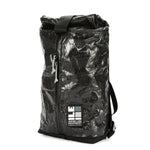 A black Apex Day Pack with a zippered main compartment and a roll-top Pleated interior pocket, featuring an adjustable shoulder strap and a padded back panel. The pack is shown against a white background.