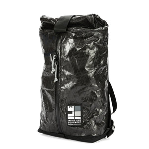 A black Apex Day Pack with a zippered main compartment and a roll-top Pleated interior pocket, featuring an adjustable shoulder strap and a padded back panel. The pack is shown against a white background.